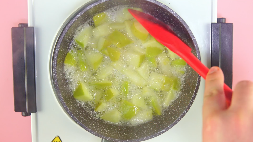Apples cooking in liquid, bubbling away in a pot