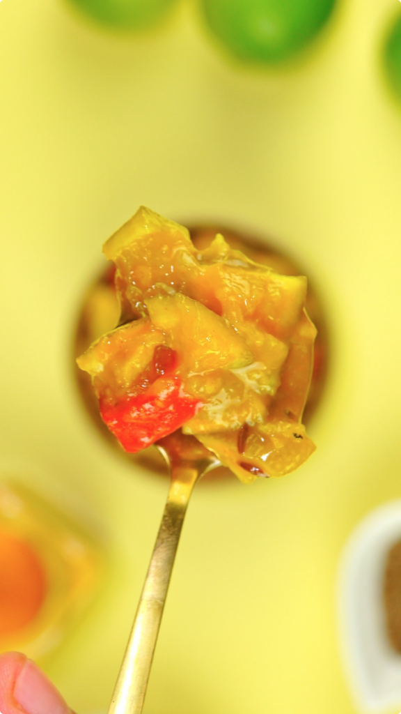 A close up of a spoonful of lime and ginger chutney with out of focus background