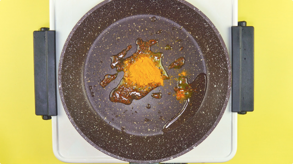 CUmin seeds and ground turmeric in oil in a skillet